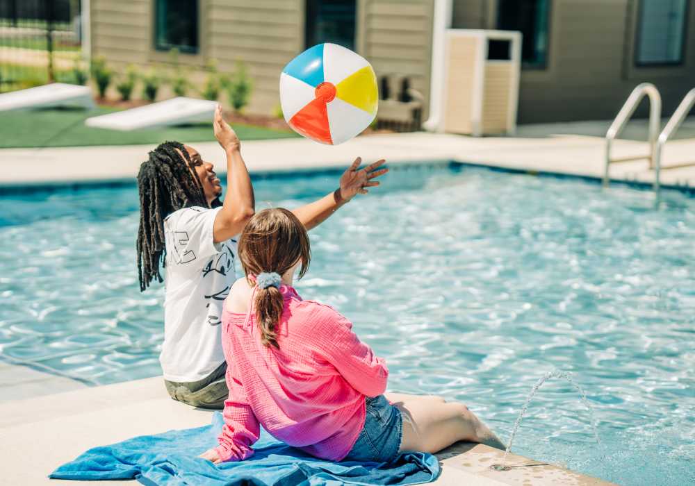 Residents playing with a ball on the edge of a pool at The Waters at Promenade in Marrero, Louisiana