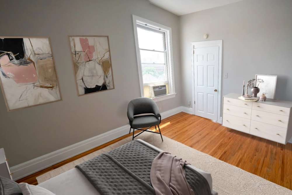 Well-lit bedroom with ceiling fan, large window, and hard-wood style flooring at À L'aise Hyde Park in Cincinnati, Ohio