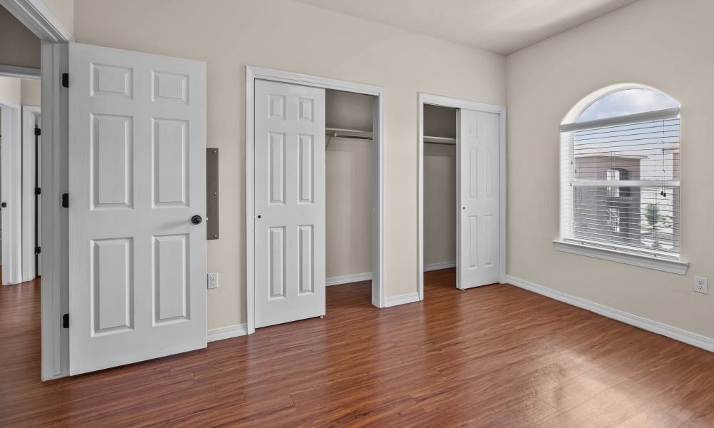 Bedroom with a large window and a door leading to walk-in closet area at Las Torres Apartments in El Paso, Texas