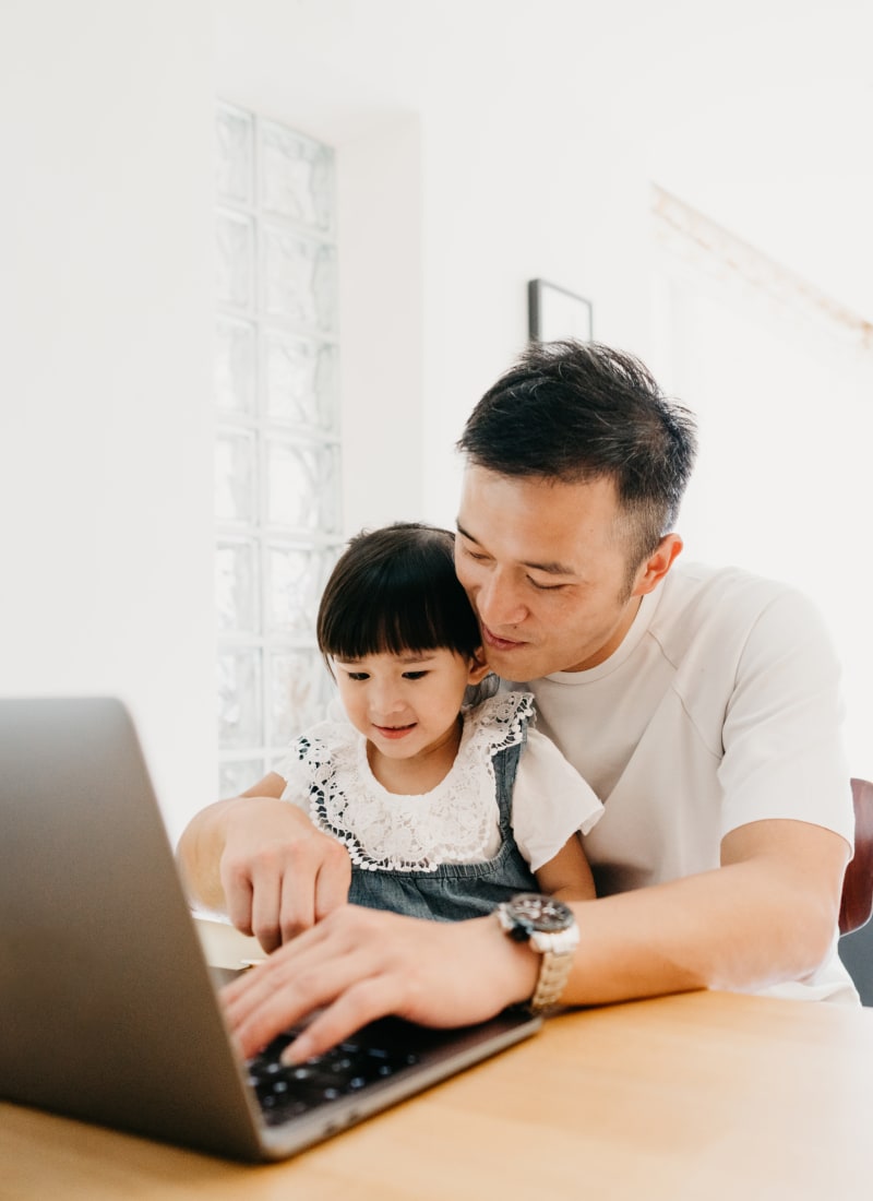 Resident working on his computer with his daughter at Marquis of Carmel Valley in Charlotte, North Carolina