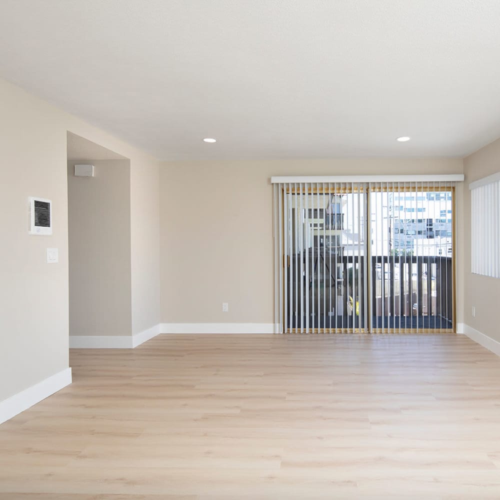 Spacious living area with wood-style flooring and sliding glass door to a balcony at Villa Capri in San Diego, California