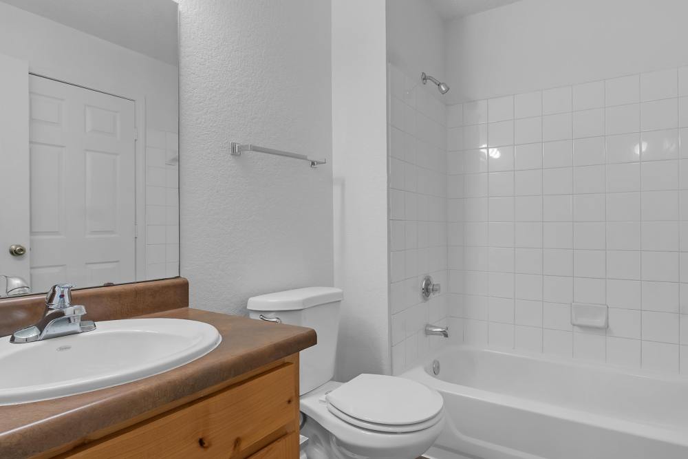 Bright bathroom with vanity light, mirror, sink,, commode and bathtub at Garden Courtyards in Tulsa, Oklahoma