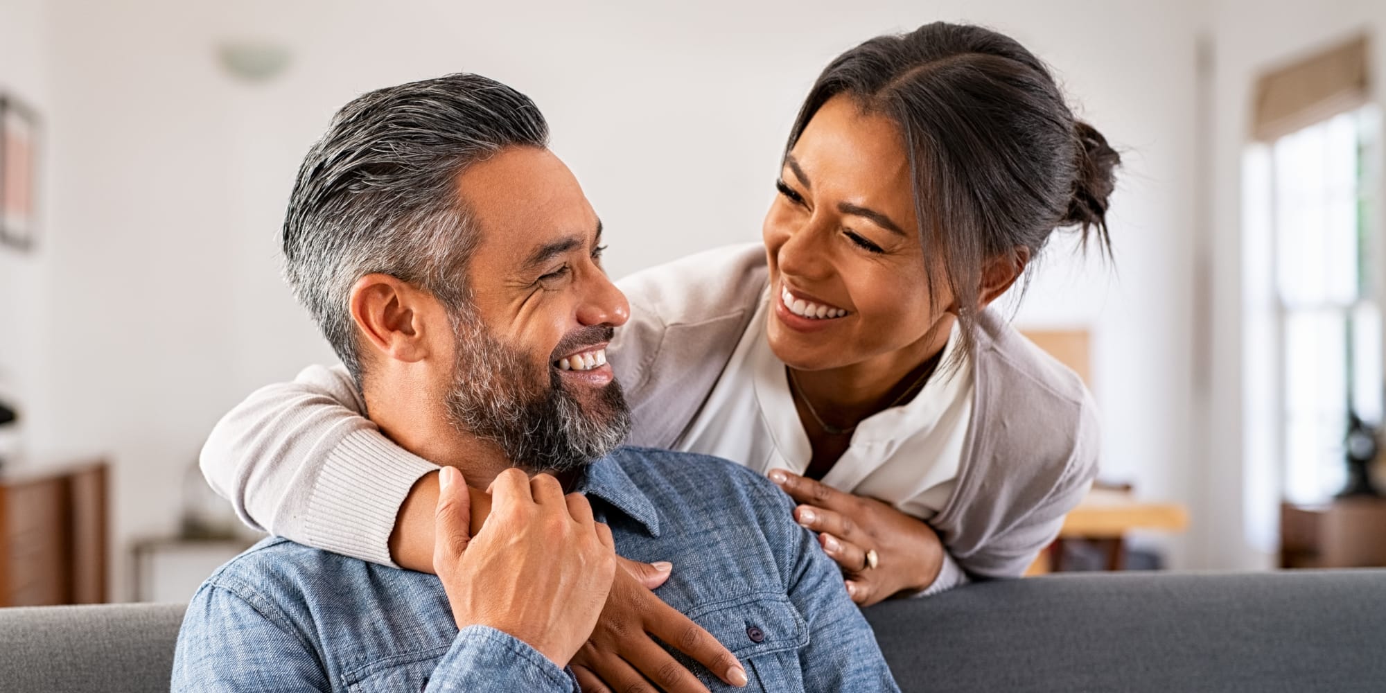 A woman hugging her husband on their couch at Regency Apartments in Lawton, Oklahoma