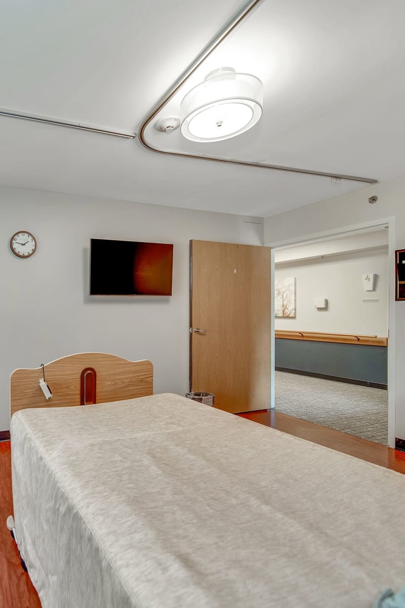 Single-resident room with a wheel-bed and tv at Fair Oaks Health Care Center in Crystal Lake, Illinois