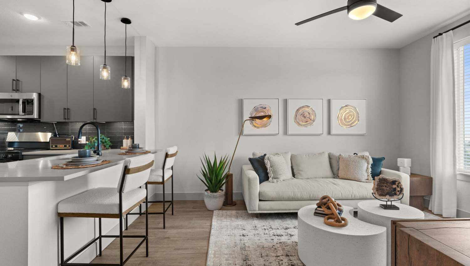 Living room with ceiling fan and large window  at The Lock at Flatirons in Broomfield, Colorado