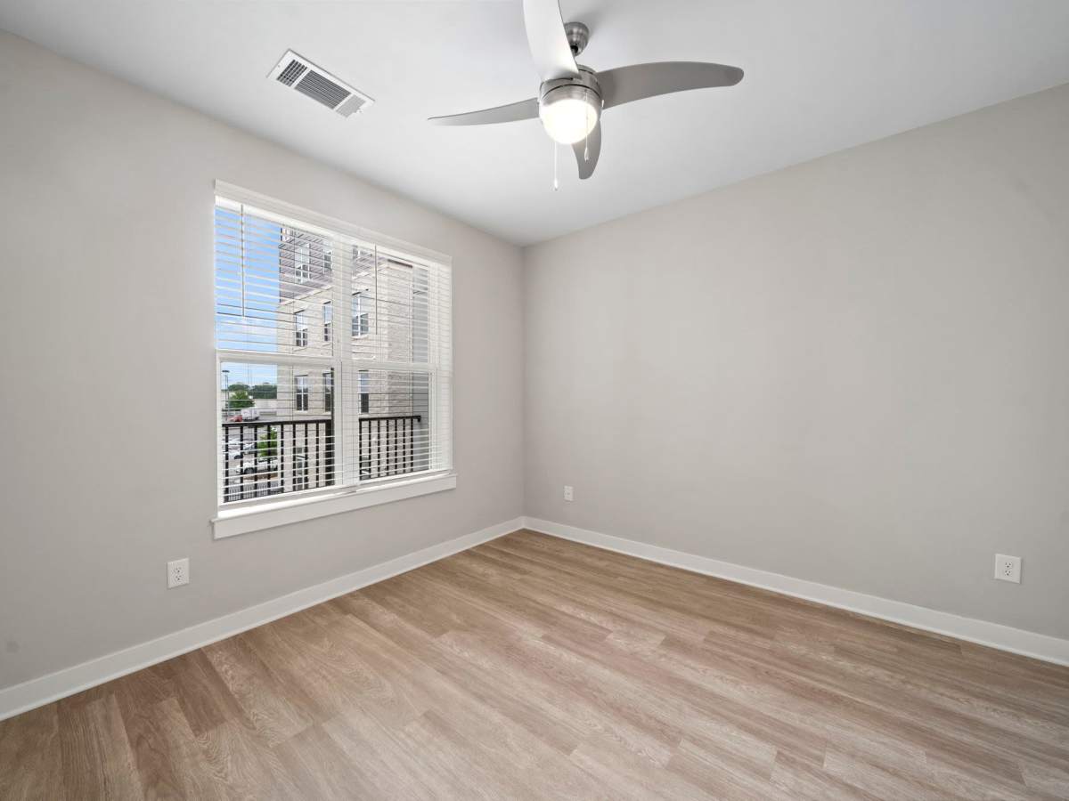 Unfurnished bedroom with ceiling fan, wood-style flooring and large window at The Rise at Regency in Henrico, Virginia