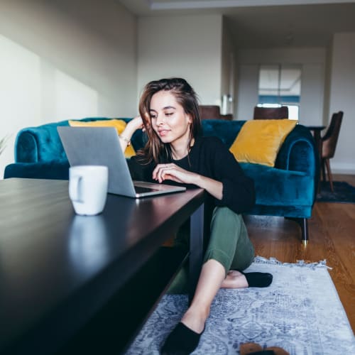 Resident getting some online work done in her well-furnished student apartment's living area at IDENTITY Logan Park in Berkeley, California