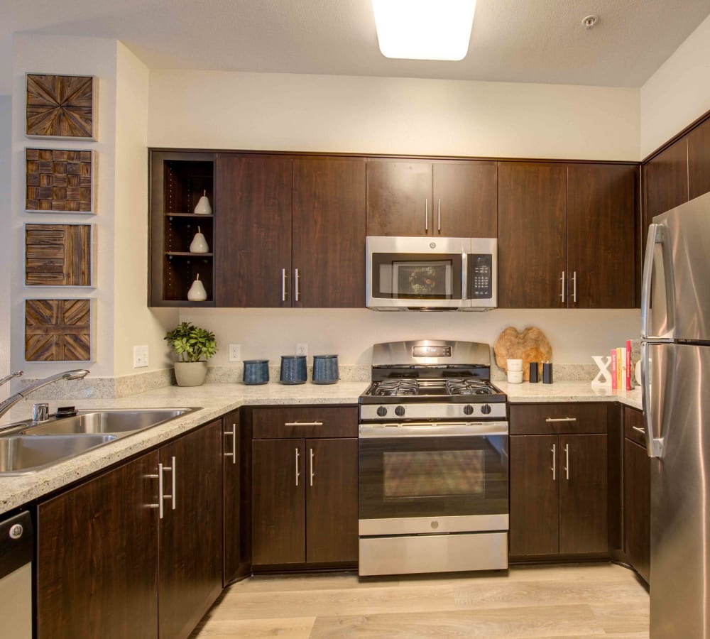 Chef-inspired kitchen with dark wood cabinetry and hardwood flooring in a model home at Sofi Warner Center in Woodland Hills, California