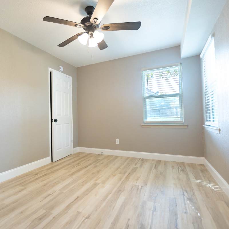 Bedroom with windows and ceiling fan at Lakeshore Villa Apartments in Rowlett,Texas