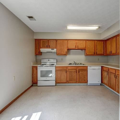 Apartment kitchen with wooden cabinets and white appliances at Edwards Crossing I in Beaver, West Virginia
