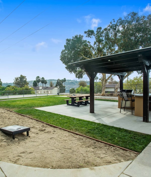 Exterior Amenity Area with Corn Hole and Covered BBQ and Picnic Area at Shadow Ridge Apartments in Oceanside