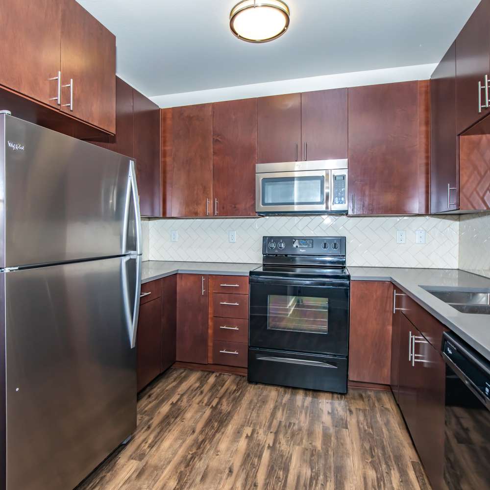 Apartment kitchen with stainless-steel appliances and wood cabinet at Park Place Olde Town Apartments in Arvada, Colorado