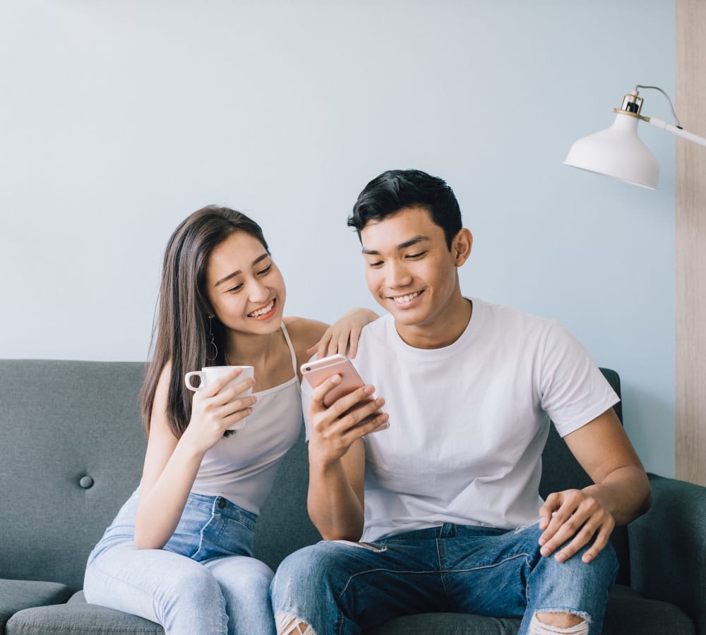 Resident checking his phone while sitting on the couch with a friend at Sofi Parc Grove in Stamford, Connecticut