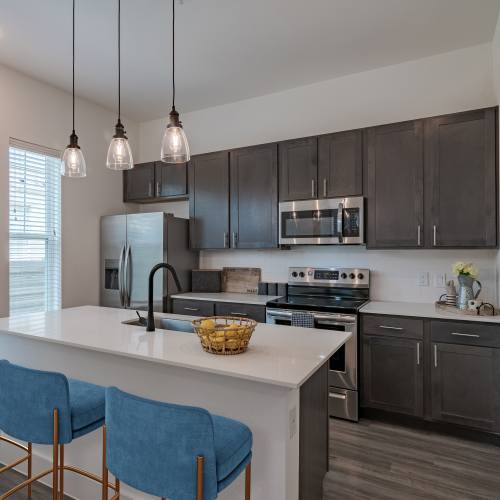 Open concept model living room and kitchen with faux wood flooring at Elevate at Skyline in McKinney, Texas