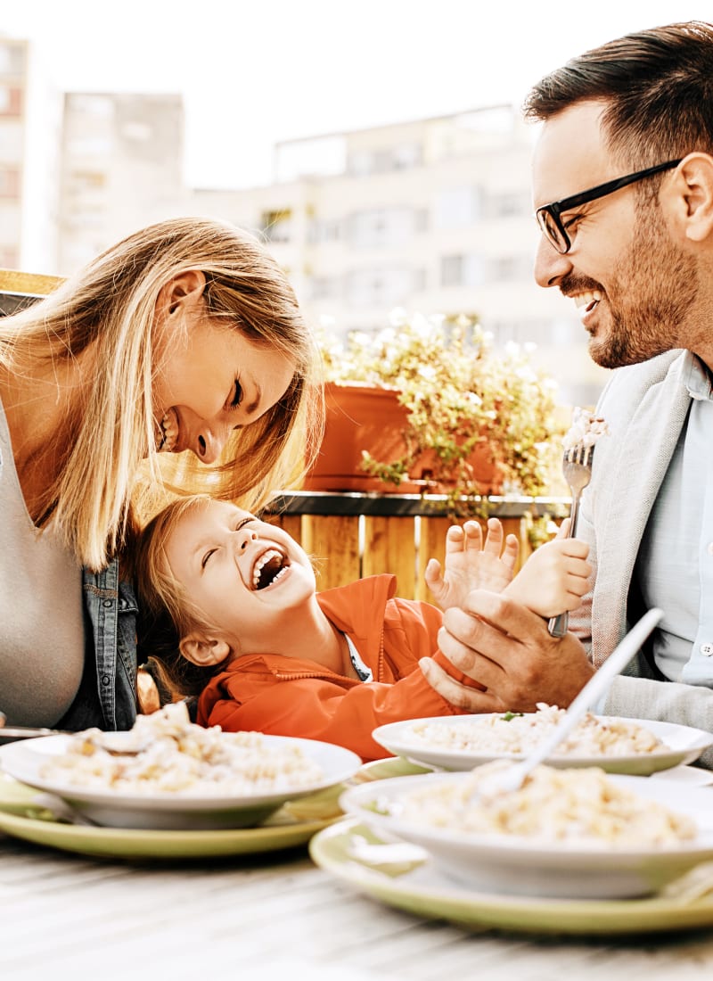 Parents and child laughing while enjoying dinner near Marquis at Katy in Katy, Texas