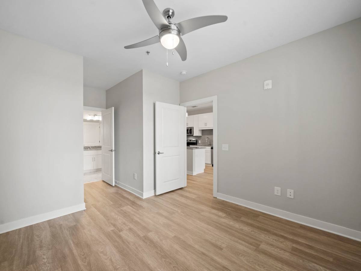 Master bedroom with wood-style flooring and attached bathroom at The Rise at Regency in Henrico, Virginia