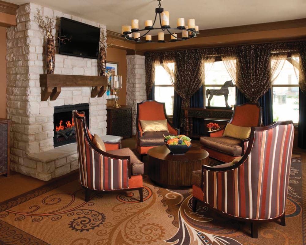 Cozy common area at Isle at Cedar Ridge in Cedar Park, Texas, with a fireplace and comfortable chairs.