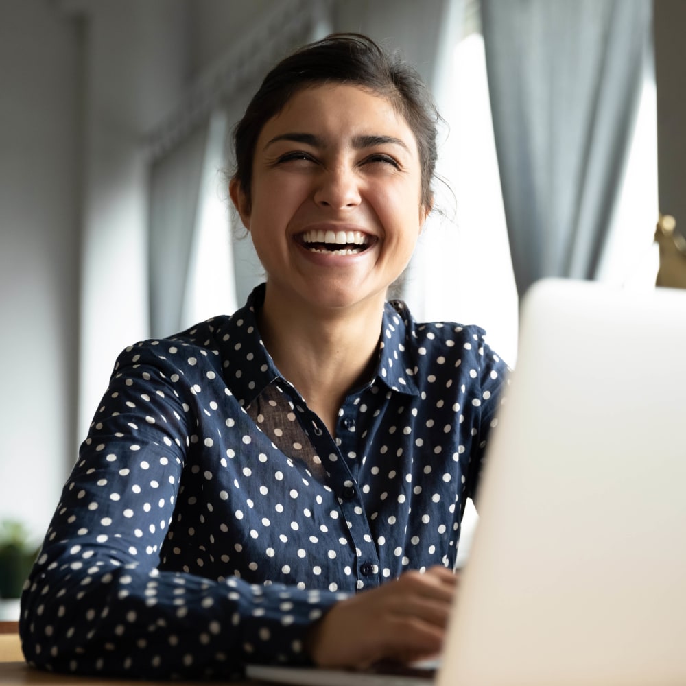 Resident smiling and working on a laptop at Bellrock Market Station in Katy, Texas