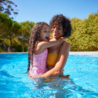 A smiling mother holding her daughter in the swimming pool at Heritage at Riverstone in Canton, Georgia