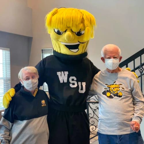 Residents posing with a sports mascot at Oxford Villa Active Senior Apartments in Wichita, Kansas