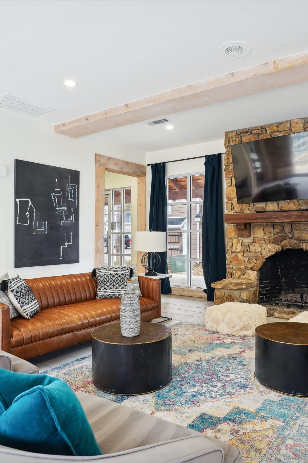 A cozy living room at the Park at the Springs, featuring comfortable seating and large windows with a view of nature at Andover Park at Flatiron District at Austin Ranch in The Colony, Texas