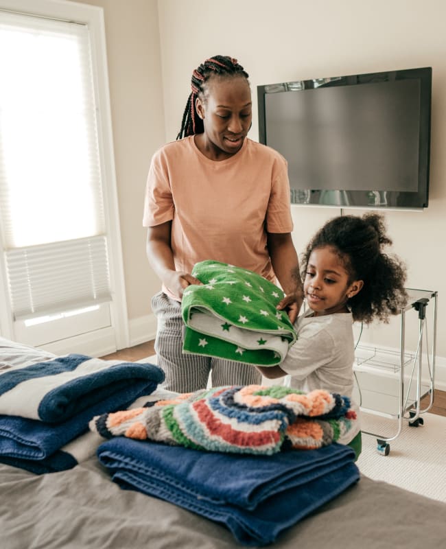 Resident and her daughter folding laundry in their spacious bedroom at Glenmont Crossing in Wheaton, Maryland