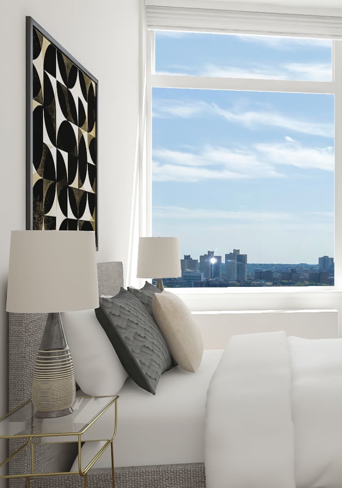 Model bedroom with natural light from a large window at The Alexander in Rego Park, New York