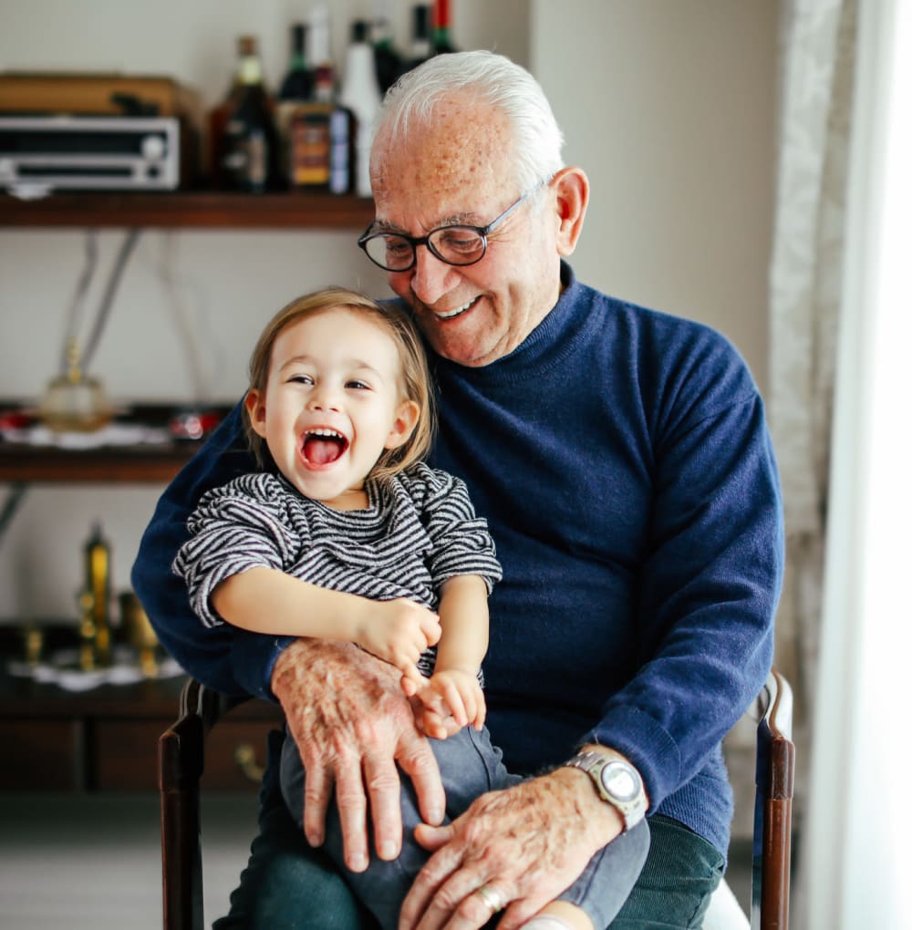 Resident sitting in a chair with his grandson at a Blossom Collection community