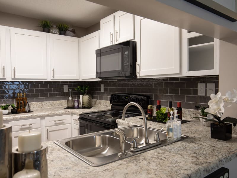 White cabinets and black appliances in an apartment kitchen at Renaissance at Galleria in Hoover, Alabama