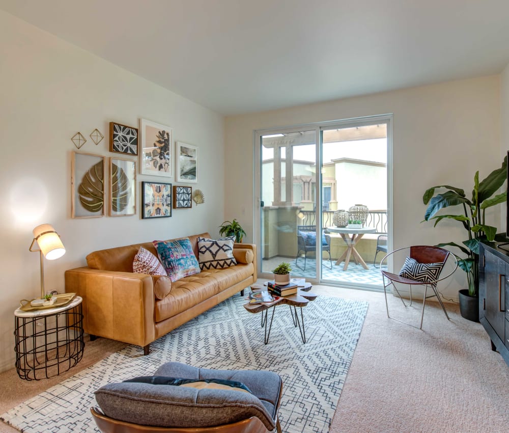 Cozy living room with a sliding door to the private balcony outside a model home at Sofi at Topanga Canyon in Chatsworth, California