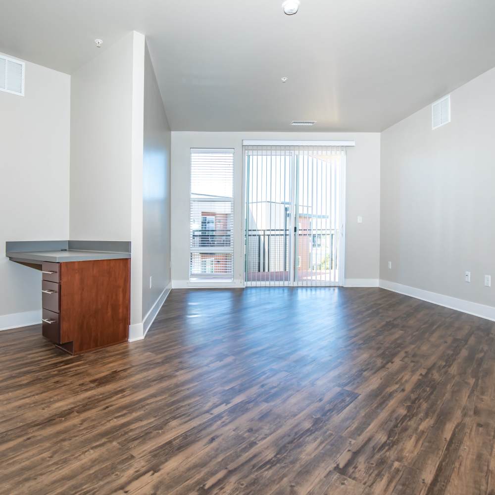 Spacious unfurnished living room with desk, hard wood flooring and access to patio at Park Place Olde Town Apartments in Arvada, Colorado
