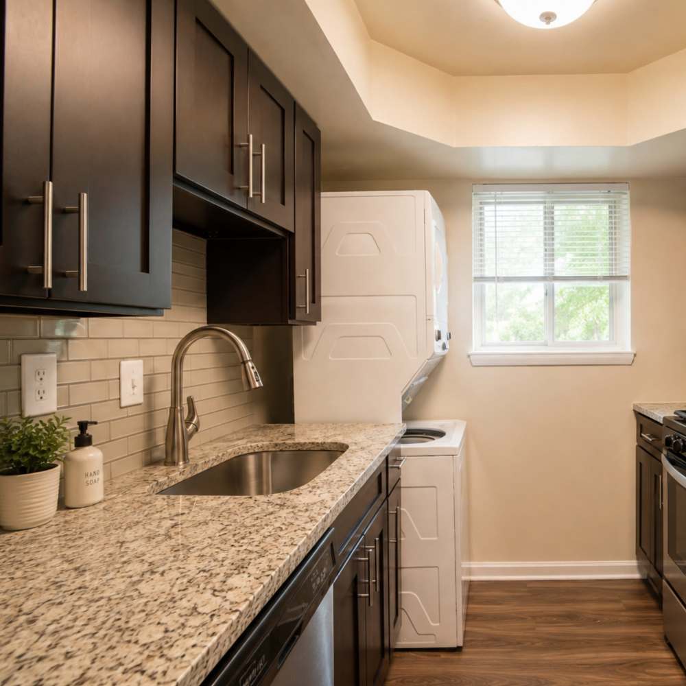 Kitchen with espresso cabinets, granite countertops, and in-unit stacked laundry at Glen Ridge Apartment Homes in Glen Burnie, Maryland
