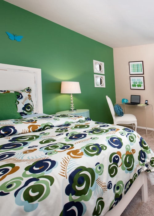 Model bedroom with a green accent wall and a desk at James River Pointe in Richmond, Virginia