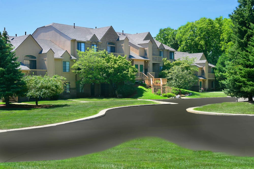 Building exterior and professionally landscaped grounds with mature trees at Saddle Creek Apartments in Novi, Michigan