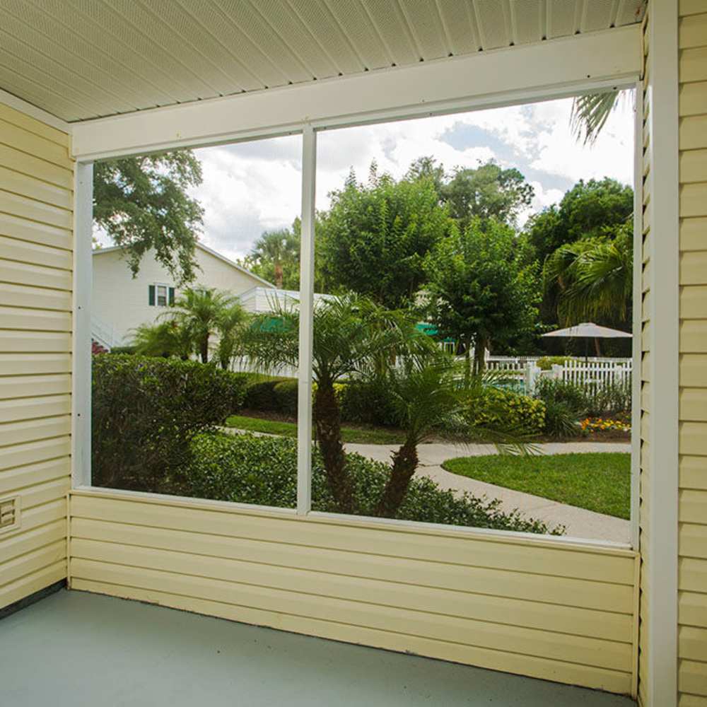 Serene view of lush landscaping and tranquil gardens from a charming porch at Park Place Apartments in Port Richey, Florida.