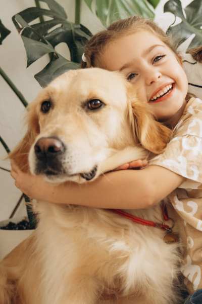 Girl hugging golden retriever with plants nearby Valley Brook Townhomes in Rochester, New York