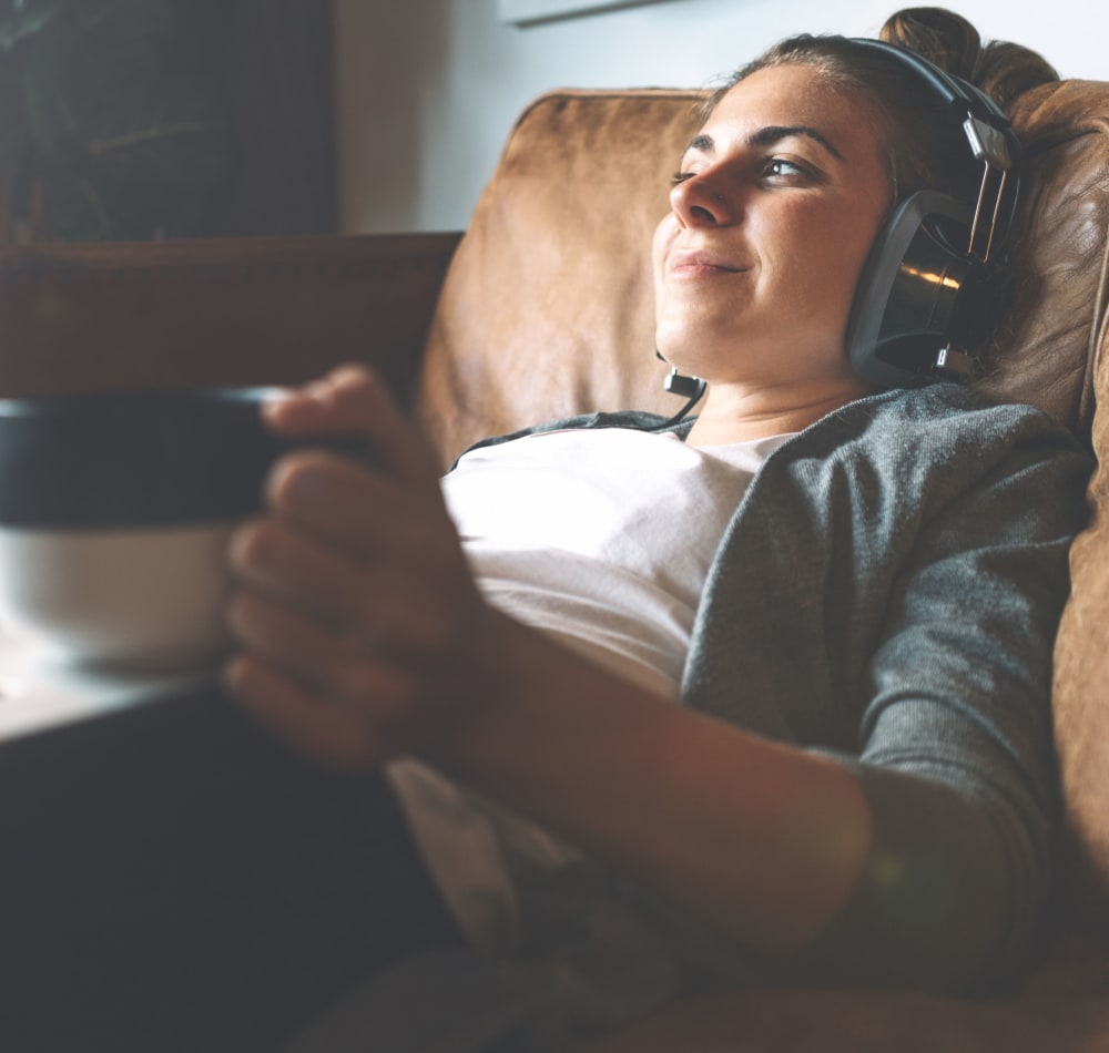 Resident relaxing with coffee and headphones and working on computer at Terra Apartment Homes in Federal Way, Washington