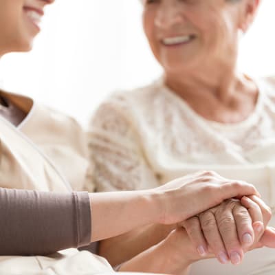 Resident smiling and holding hands with on-site nurse at Westminster Memory Care in Lexington, South Carolina