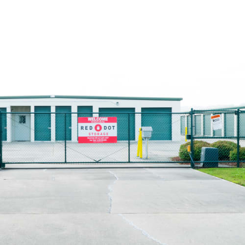 Outdoor storage units with green doors behind a fence at Red Dot Storage in Port Allen, Louisiana