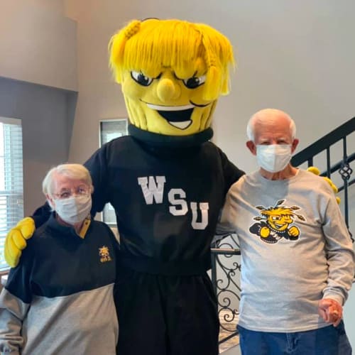 Residents standing with a sports mascot at Oxford Villa Active Senior Apartments in Wichita, Kansas