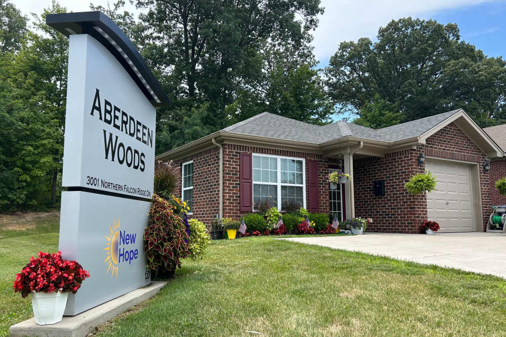 Charming brick home with vibrant flower beds and inviting entrance at Aberdeen Woods in Jeffersonville, Indiana