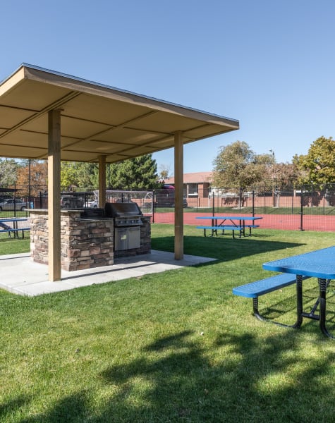Exterior Covered BBQ Area with Picnic Table, Sport Court in the background at Shadowbrook Apartments in West Valley City