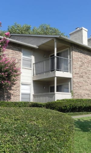 Exterior with private balconies and well-manicured hedges at Highlands of Duncanville in Duncanville, Texas