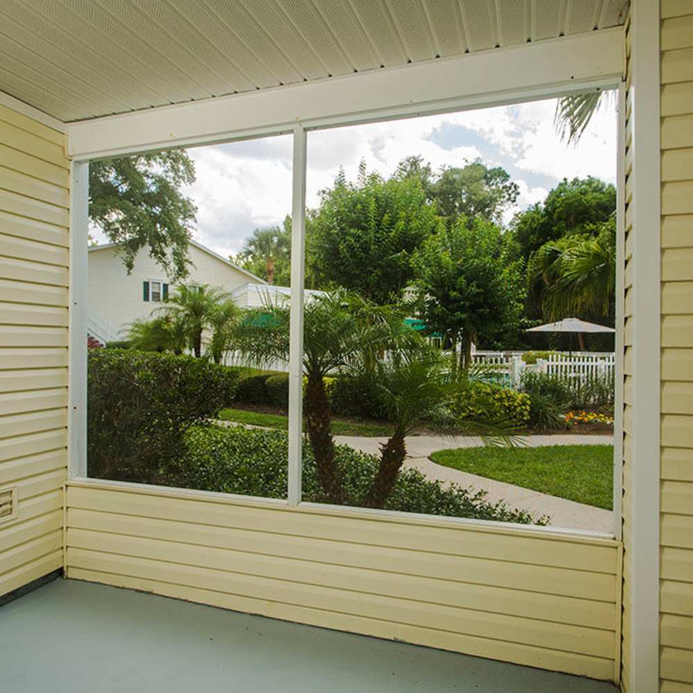 Charming sunlit porch overlooking lush landscaping at Park Place Apartments in Port Richey, Florida.