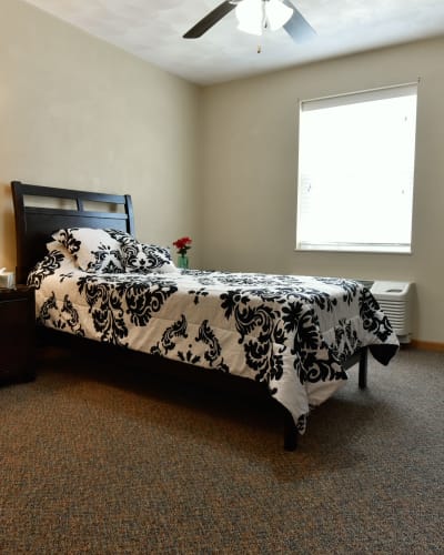 Model resident bedroom with a large window at Garden Place Waterloo in Waterloo, Illinois.