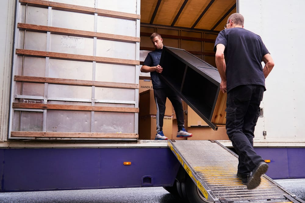 Two men loading furniture into a moving truck at A-American Self Storage in Reno, Nevada