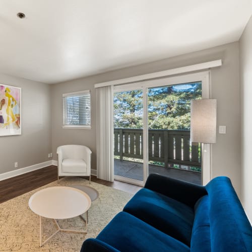 Living room with sliding doors opening onto a private balcony at Summerhill Terrace Apartments in San Leandro, California