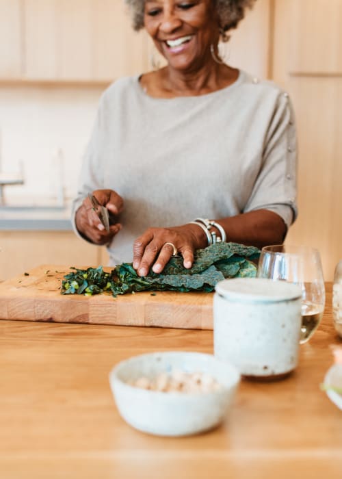 A woman chopping vegetables in a kitchen at The Pillars of Prospect Park in Minneapolis, Minnesota