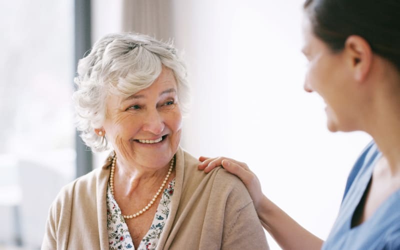 Resident smiling and helpful caregiver at Blossom Collection in Rochester, Michigan