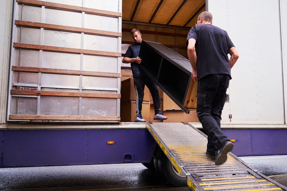 Two men loading furniture into a moving truck at A-American Self Storage in El Cajon, California